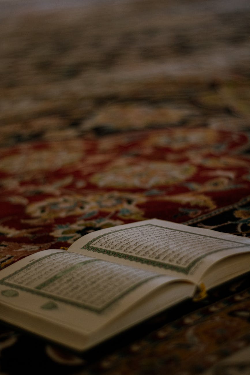 a quran on a carpet with a book on top