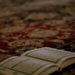 a quran on a carpet with a book on top