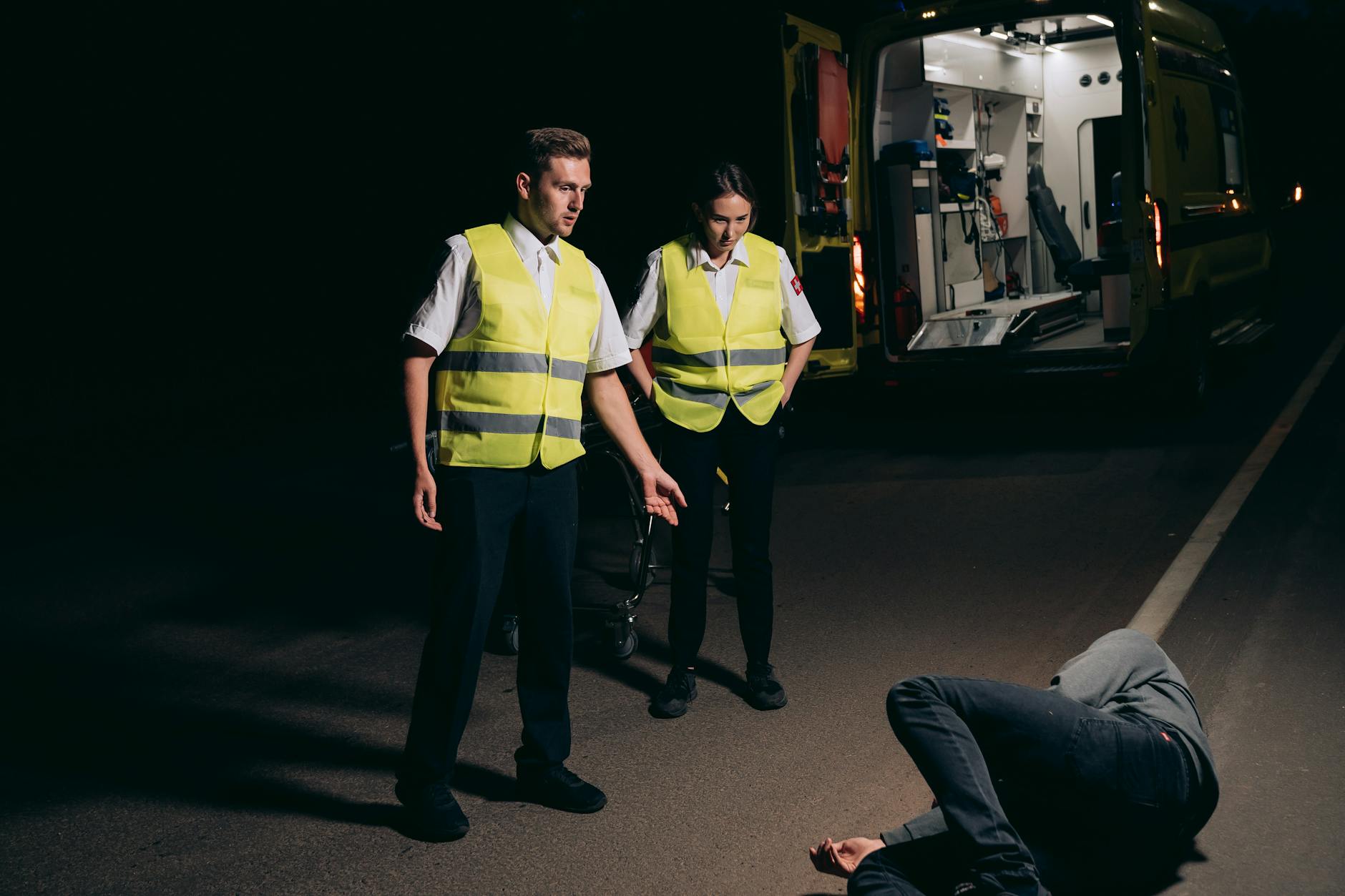 paramedics looking at the person lying on the street